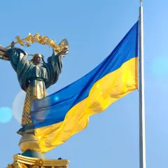 Pomnik z wieńcem laurowym i flaga Ukrainy na tle błękitnego nieba. Duma i nadzieja na wolność na Ukrainie.