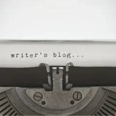 Maszyna do pisania z napisem "writer's blog...". Zastanawiasz się, jak napisać bloga po angielsku? Zacznij od tego!