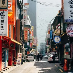 Ulica w Korei z neonami i szyldami, gdzie można usłyszeć "dzień dobry po koreańsku" (안녕하세요).
