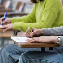 Uczniowie piszą egzamin CAE. Skupieni, z długopisami w dłoniach, wypełniają karty pracy.