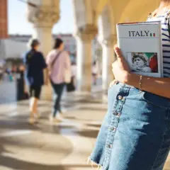 Dziewczyna z przewodnikiem po Włoszech, z piękną odmianą krajobrazu w tle.