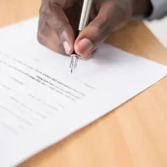 Dłoń podpisuje dokument piórem. To ważny krok, który może być częścią nauki angielskiego na poziomie B2, np. przy podpisywaniu umowy o pracę.