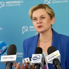 Kobieta w niebieskiej marynarce przemawia do mediów, omawiając zmiany w karcie nauczyciela.