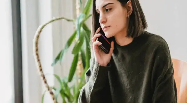 Młoda kobieta, jobseeker, rozmawia przez telefon, jej mina sugeruje rezygnację.