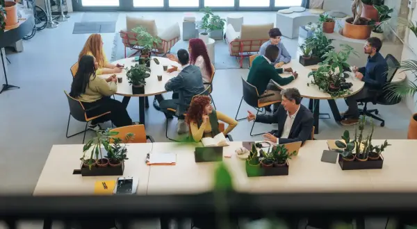 Ludzie pracują i rozmawiają w jasnej przestrzeni, która pokazuje, coworking co to.