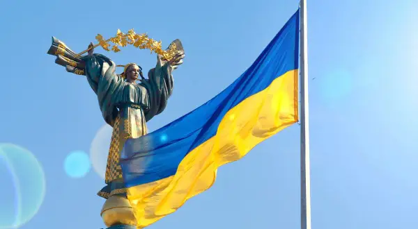 Pomnik z wieńcem laurowym i flaga Ukrainy na tle błękitnego nieba. Duma i nadzieja na wolność na Ukrainie.
