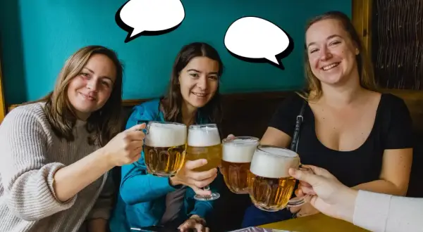 Trzy uśmiechnięte kobiety wznoszą kufle piwa. Jedna z nich mówi "Dzień dobry po czesku!".