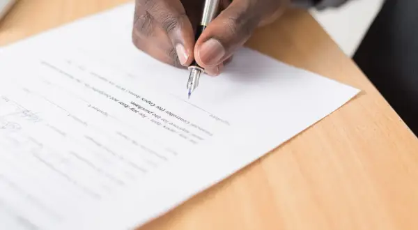 Dłoń podpisuje dokument piórem. To ważny krok, który może być częścią nauki angielskiego na poziomie B2, np. przy podpisywaniu umowy o pracę.