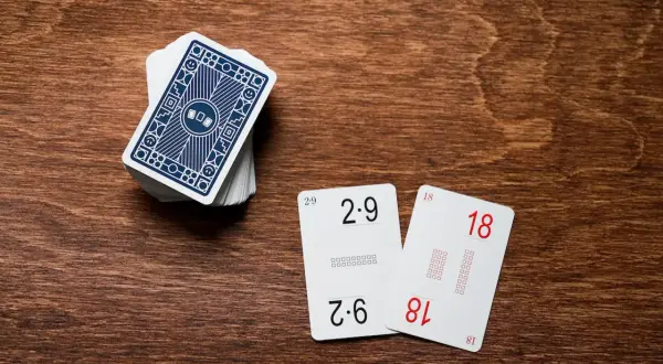 Karty do nauki tabliczki mnożenia: 2x9=18 i 6x3=18. Stos kart z niebieskim wzorem.
