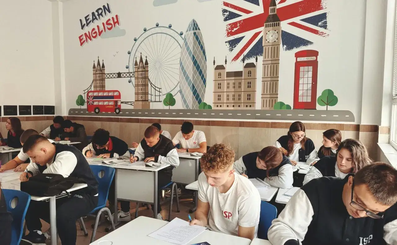 Uczniowie piszą egzamin FCE w sali lekcyjnej ozdobionej motywami Londynu.